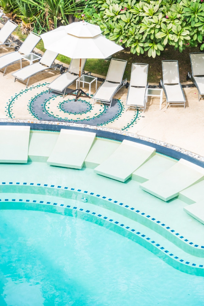 A Serene Pool Area Featuring Lounge Chairs And Umbrellas For Relaxation Under The Sun