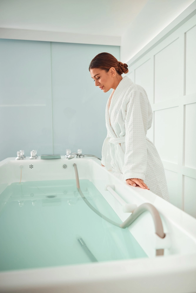 A Woman In A Bathrobe Stands In A Bathtub